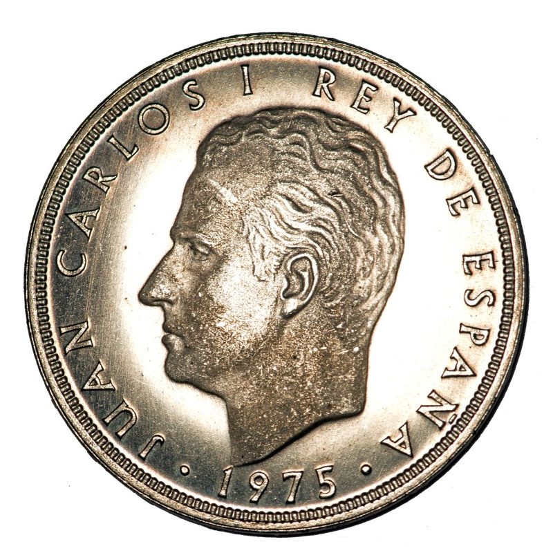 Cabeza de Juan Carlos I a la izquierda con la leyenda y la fecha 1975.
